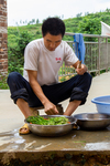 Duan Wenbin preparing onions outside. by Marie Anna Lee