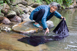 Wu Meitz washes fabric in river