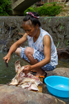 Woman chopping fresh pork by river
