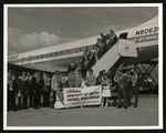 Football-University of the Pacific team members wearing leis next to United Airlines plane by unknown