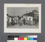 Mixed group with luggage; buildings in background #1: (R-L) Hippo Ito, Bob Sasaki, Tak Kubota, Shig Ho, Benny Okura, Max Kenmatsu, Mr. Okura