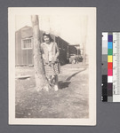 One woman #25 [next to tree; in front of building]