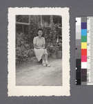One woman #63 [seated in front of ivy-covered building]