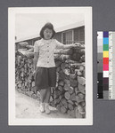 One woman #98 [standing by woodpile]