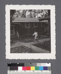 Woman walking between rows of houses [9-12-E] by Richard Shizuo Yoshikawa